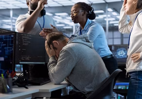 Frustrated programmer surrounded by coworkers