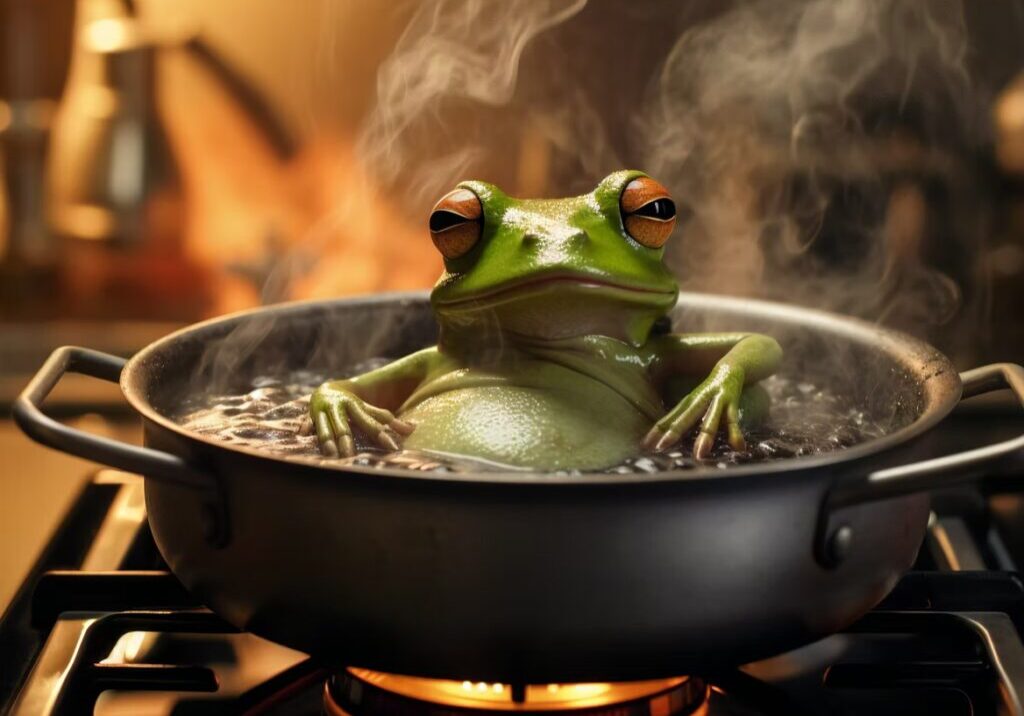 A frog sitting in a steaming frying pan on a stove.